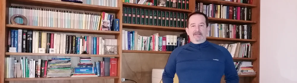 Un uomo in piedi davanti a uno scaffale di libri