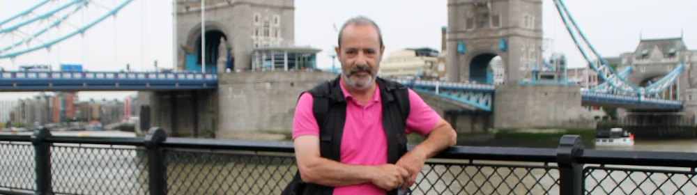 Un uomo in piedi vicino a una ringhiera con un ponte sullo sfondo