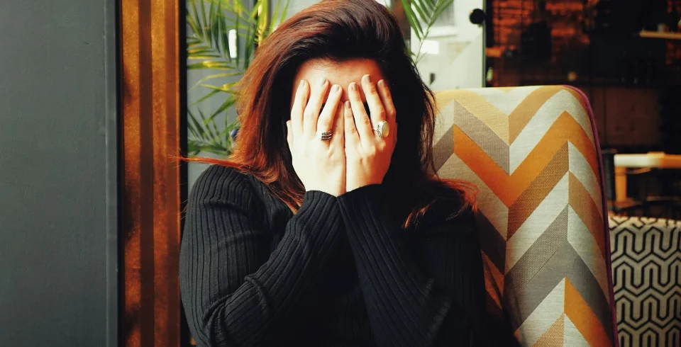 une femme se couvrant le visage avec ses mains
